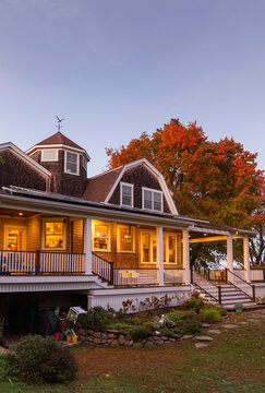 Vertical of Craftsman home with porch in Autumn at sunset with woman
