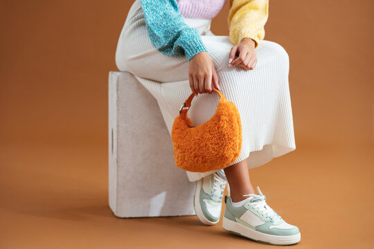 Crop stylish woman sitting on box