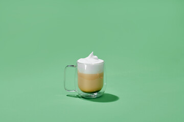 Cappuccino in glass cup with double walls isolated on green background