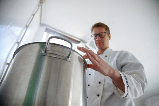 Worker cook cheese in a saucepan in a cheese factory