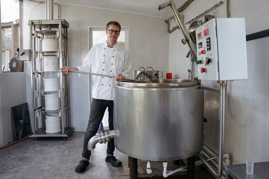 A worker at a cheese factory cuts cheese in a pasteurizer
