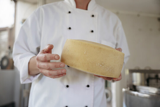 A cheese maker holds cheese in his hands