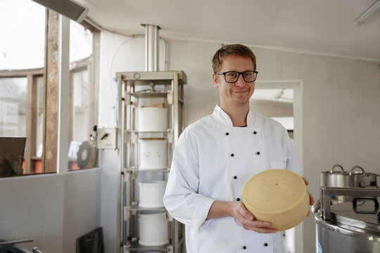 A cheese maker holds cheese in his hands