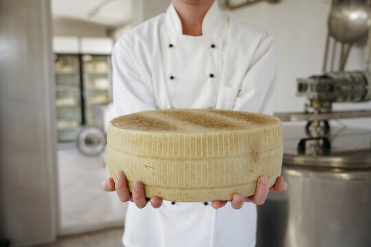 A cheese maker holds cheese in his hands