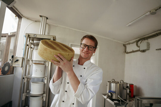 A cheese maker holds cheese in his hands