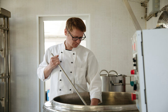 A worker at a cheese factory cuts cheese in a pasteurizer