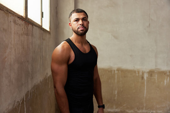 Confident athletic guy standing  in shabby gym