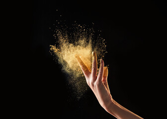 Female hand with yellow colored sand.