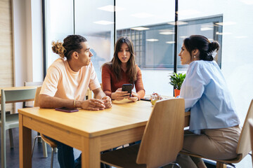 Coworkers having coffee and using smartphone in coworking