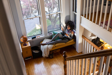 Black Girl at home relaxing listens to music on bluetooth speaker 