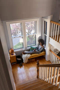  Girl at apartment drawing with ipad tablet computer in cozy nook 