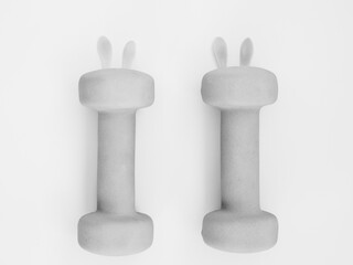 two black and white heavy dumbbells with leaves in shape of Easter bunny on grey background. Easter...
