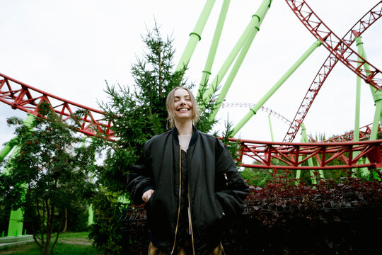 Happy woman at roller coaster in amusement park
