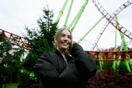 Happy woman at roller coaster in amusement park
