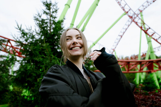 Happy woman at roller coaster in amusement park
