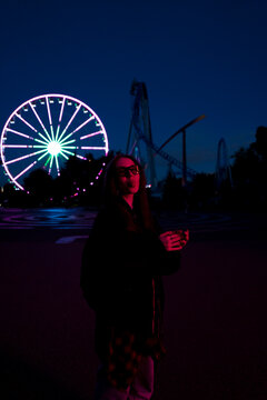 young stylish woman posing in illuminated amusement park