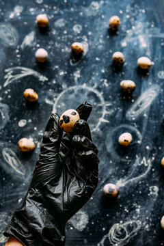 A hand in a black rubber glove holds an egg.