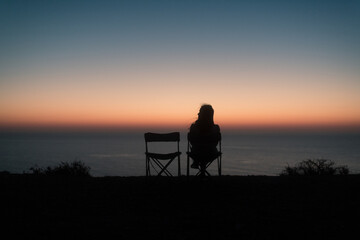 Happy sitting couple enjoying sunset sea view