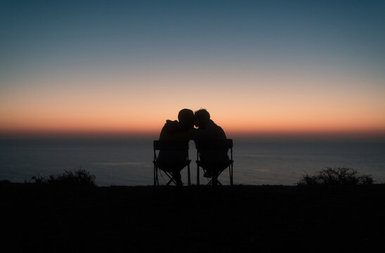 Kissing couple enjoying peaceful sunset near the ocean