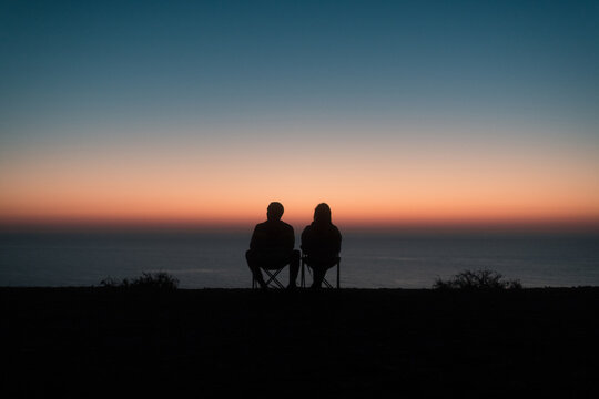 Anonymous couple silhouettes enjoying sunset sea view