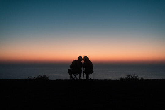 Kissing couple silhouettes during peaceful sunset