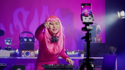 Dj performing electronic music recording process with smartphone camera, mixing techno sound using professional mixer console. Smiling artist playing song during night time in club