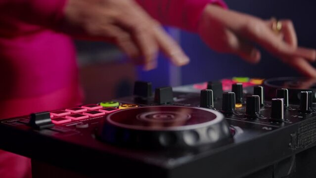 Musician standing at dj table mixing sound using professional mixer console, performing new album during night party in club. Artist enjoying playing music using audio equipment. Close up
