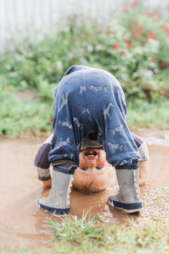 toddler boy looking through his legs in a puddle