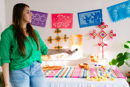 Woman with palo santo setting up Mexican altar