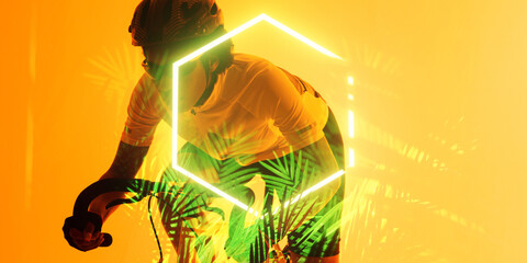 African american female athlete riding bike by illuminated hexagon and plants on yellow background