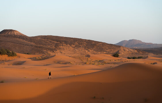 Woman walking in dunes of Sahara desert, Morocco.