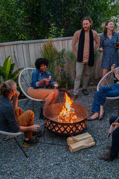 Friends hanging out together by a firepit in an urban yard 
