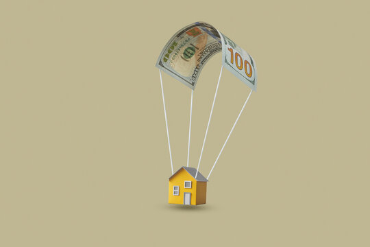 Yellow paper house on dollar parachute.