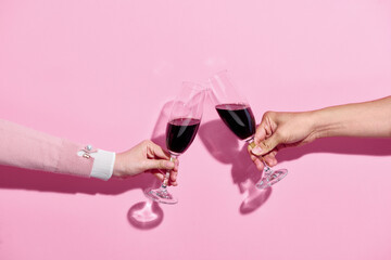 Man and Woman hands toasting with wine on pink background