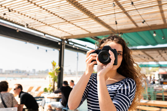 Young girl taking photos from terrace bar near the sea