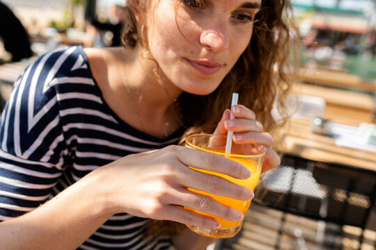 Crop woman drinking juice at terrace bar