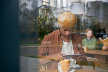 A Black Man Using Tablet At A Cafe