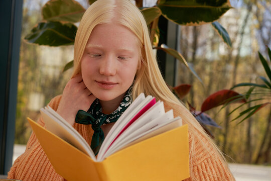 Albino girl reading a book in a café