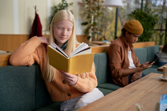 Focused female reading book in cafeteria