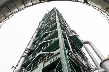 A tall oil refining tower against a gray sky