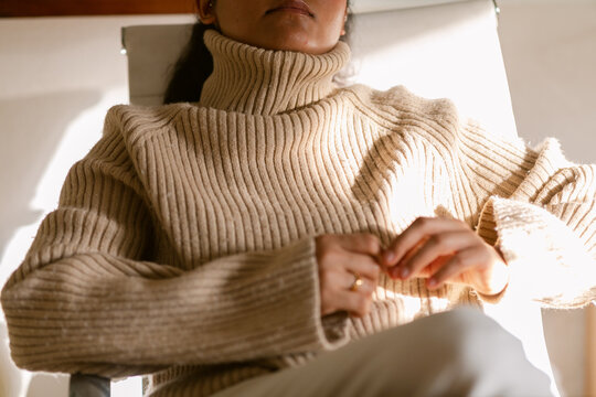 Relaxed woman in neutral garment relaxing on chair