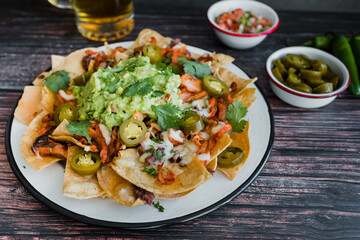 Mexican Nachos with cheese or tortilla chips with meat, avocado and beer, tex mex food in Mexico America