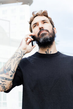 bearded man with tattoos using his mobile phone 