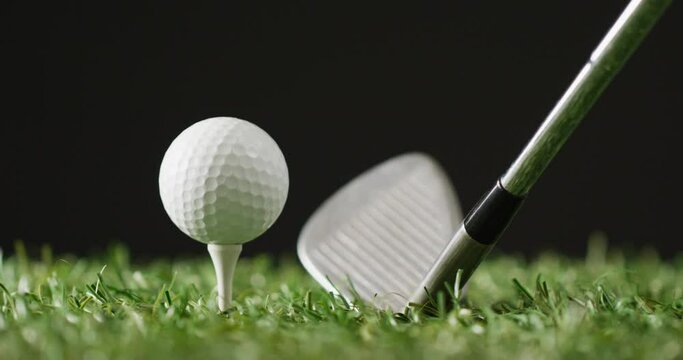 Close up of golf club and ball on grass and black background, copy space, slow motion