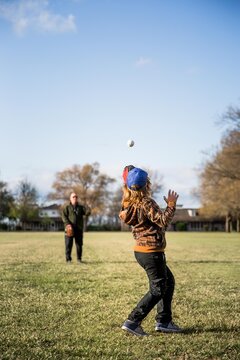 Father and son playing catch in a field in a neighborhood 