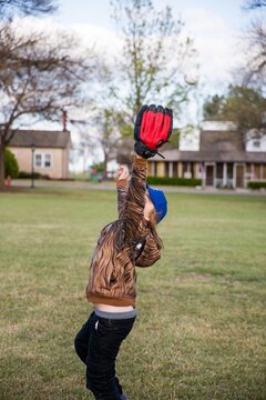 Boy playing catch in a field in a neighborhood 