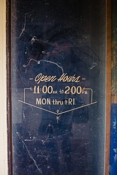 Dusty old business door with open hours 11:00-2:00