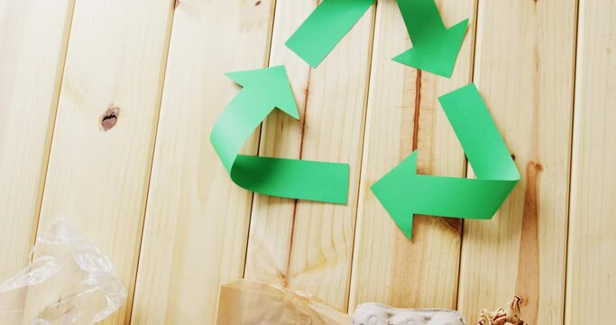 Close up of trash and recycling symbol of green paper arrows on wooden background, with copy space
