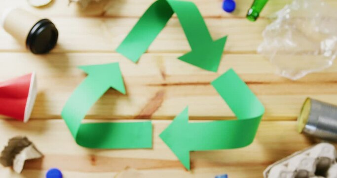 Close up of trash and recycling symbol of green paper arrows on wooden background