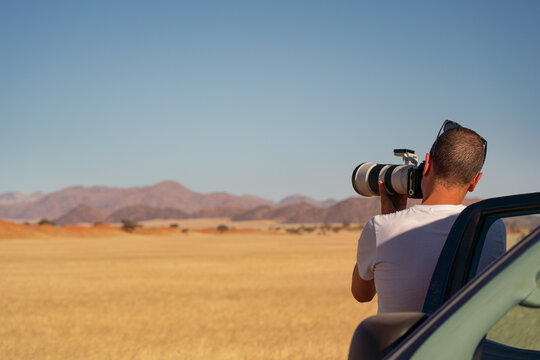 Photographer taking photos from his car in a safari day, Namibia